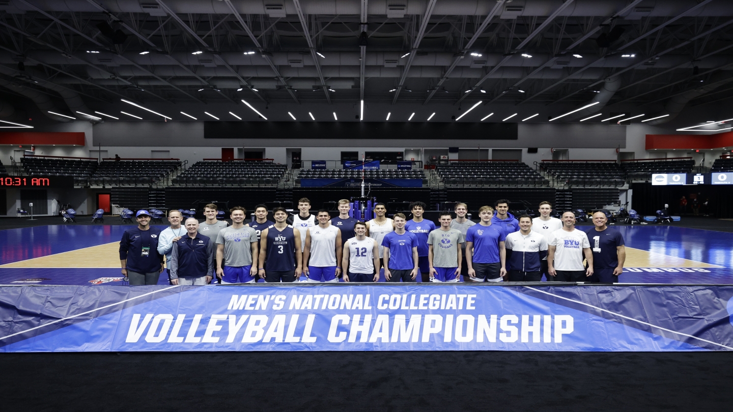 mens volleyball team standing behind national championship sign